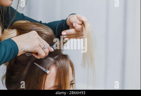 mani di donna pettinare i capelli e fare il suo cliente bouffant nel salone di bellezza Foto Stock