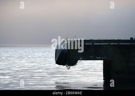 Vista di un semplice molo per una nave in acqua con nebbia in salita. Foto Stock