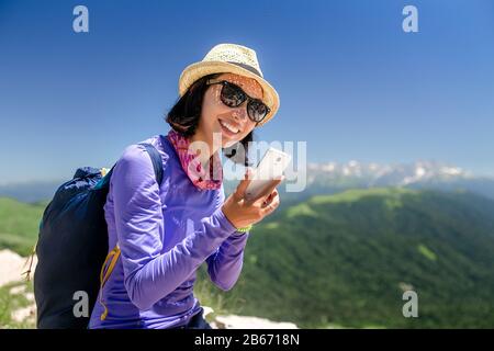 donna viaggiatore in montagna parlando su uno smartphone durante un'escursione Foto Stock