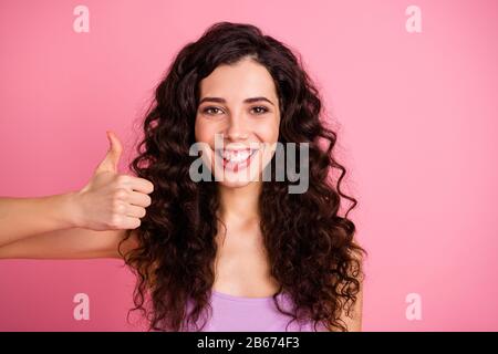 Foto di bella cute affascinante donna che consiglia qualcosa da pollici in su mentre isolato con sfondo rosa Foto Stock