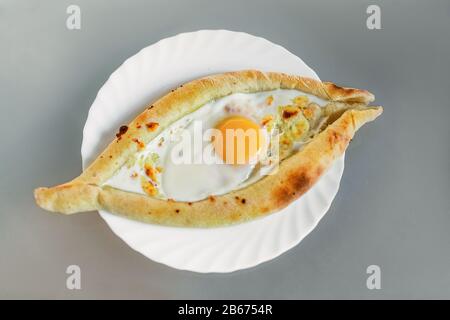 Abkhaziano o georgiano piatto nazionale Khachapuri pane con formaggio e uova su un piatto in un caffè Foto Stock