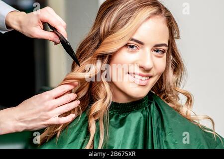 Capelli styling di donna. Felice giovane donna e parrucchiere con spazzola che fa acconciatura al salone dei capelli. Foto Stock