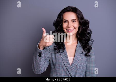 Primo piano foto di bella donna elegante che mostra il suo pollice in su sorridente promozione annunci indossando giacca blazer isolato su sfondo grigio Foto Stock