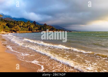 Spiaggia deserta e paradisiaca sull'isola di Ilhabela a São Paulo durante il tramonto tropicale Foto Stock