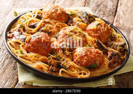 Spaghetti speziati con polpette e sugo di funghi da vicino in un piatto sul tavolo. Orizzontale Foto Stock