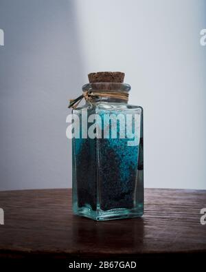 bottiglia di fantasia con sali da bagno blu per rilassanti trattamenti spa con sfondo bianco illuminato con luce naturale Foto Stock