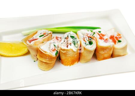 frittelle ripiene di antipasti con salmone e crema di formaggio su un piatto con limone e cipolla Foto Stock