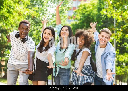 Ritratto Di Allegri Studenti Multiculturali Che Posano Con Le Mani Alzate All'Aperto Foto Stock