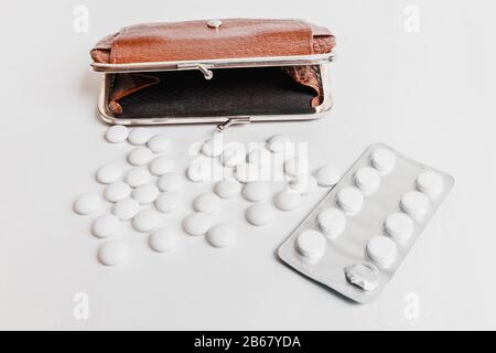 Vari farmaci e pillole con vasi vuoti e una borsa su uno sfondo bianco. Concetto del prezzo dei medicinali Foto Stock