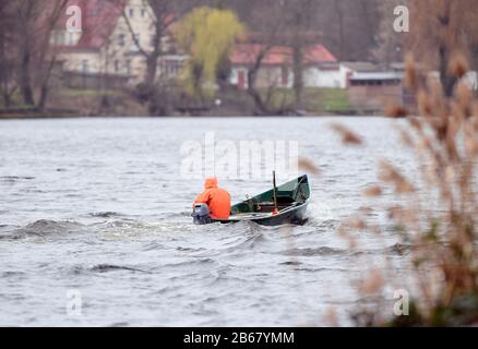 10 marzo 2020, Brandeburgo, Potsdam: Un pescatore naviga la sua barca dal porto di Potsdam in direzione di Caputh. La maggior parte dei pesci consegnati dall'allevamento di pesci Albe nella regione di Emsland sono stati trasportati in barca nelle acque circostanti dai pescatori di Brandeburgo e ivi liberati. Lo stoccaggio delle acque di Havel, con un totale di 300.000 anguille giovani, fa parte di un progetto pilota a lungo termine per coordinare le misure di stoccaggio delle anguille nello stato di Brandeburgo. Foto: Soeren Stache/dpa-Zentralbild/ZB Foto Stock