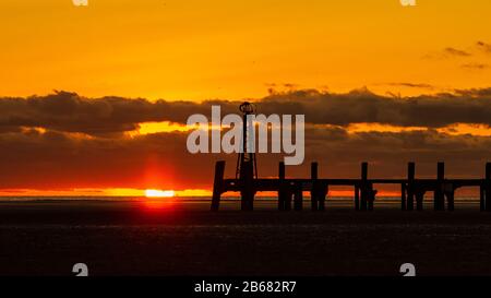 Un cielo dorato mentre il sole tramonta dietro la silhouette del molo vittoriano a St Annes on Sea nel Lancashire inghilterra Foto Stock