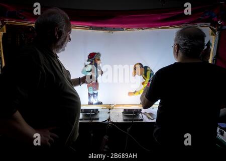 Salonicco, Grecia - 9 marzo 2020: Artisti non identificati che giocano con il personaggio principale (Karagiozis) nel teatro ombra greco dietro il cott Foto Stock