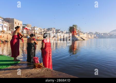 Pellegrini indù che camminano e pregano vicino al lago santo in Pushkar, India. Pushkar è una città dell'Ajmer nello stato del Rajasthan. Foto Stock