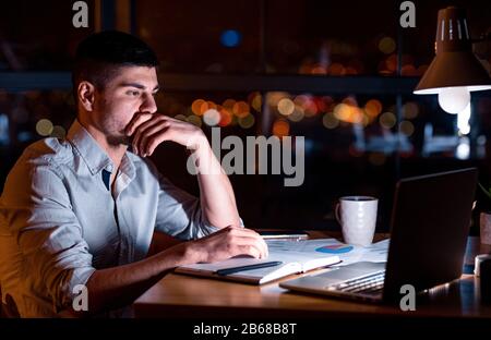 Responsabile Attento Che Lavora Sul Business Report Di Notte A Workpalce Foto Stock