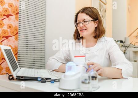 Primo piano delle mani del medico che digitano sul computer portatile un lavoratore medico seduto sul tavolo bianco - concetto medico Foto Stock