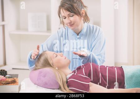 Professional guaritore Reiki facendo trattamento reiki alla giovane donna Foto Stock