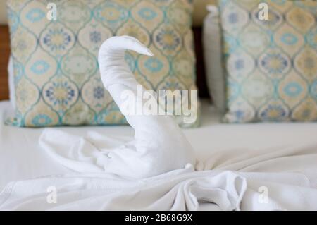 Bellissimo cigno fatto da un asciugamano bianco sul letto dell'hotel Foto Stock