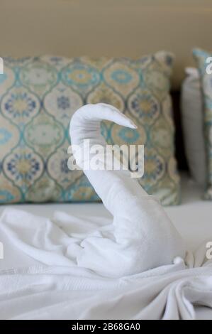 Bellissimo cigno fatto da un asciugamano bianco sul letto dell'hotel Foto Stock