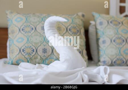 Bellissimo cigno fatto da un asciugamano bianco sul letto dell'hotel Foto Stock