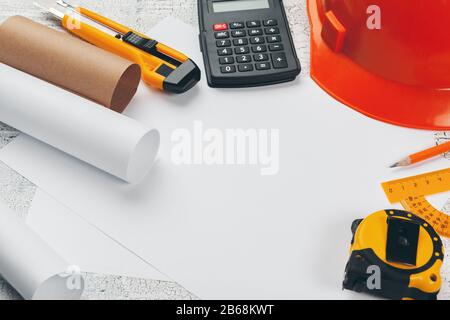 Casco di sicurezza e rotoli di disegni tecnici e materiali di consumo Foto Stock