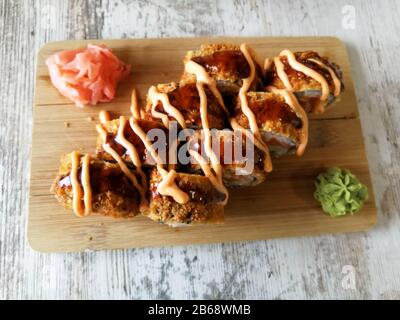 Involtini di sushi fritti caldi con salmone, formaggio e avocado con zenzero e wasabi Foto Stock