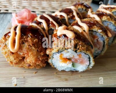 Involtini di sushi fritti caldi con salmone, formaggio e avocado con zenzero e wasabi Foto Stock
