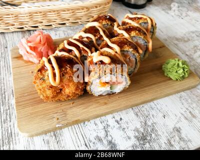 Involtini di sushi fritti caldi con salmone, formaggio e avocado con zenzero e wasabi Foto Stock