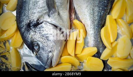 Piatto da forno con paio di pesce dorado fresco e crudo mediterraneo e patatine contorno contorno contorno preparato per la cottura. Cucina europea fatta in casa Foto Stock