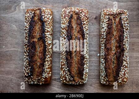 Alto angolo di chiusura di tre focacce di pane appena sfornate seminate in una panetteria artigianale. Foto Stock