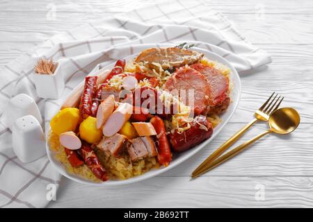 Choucroute garnie cavolo francese acido stufato con carne di maiale, salsicce affumicate e pancetta cotta con patate in vino bianco con bacche di ginepro timo, clo Foto Stock