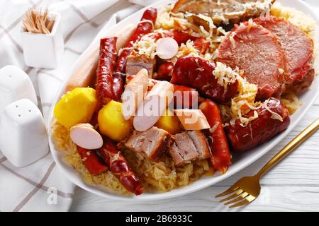 Choucroute garnie un piatto francese pasto: Cavolo acido stufato con quattro tipi di carne di maiale, salsicce affumicate, e pancetta cotta con patate brasate in whi Foto Stock