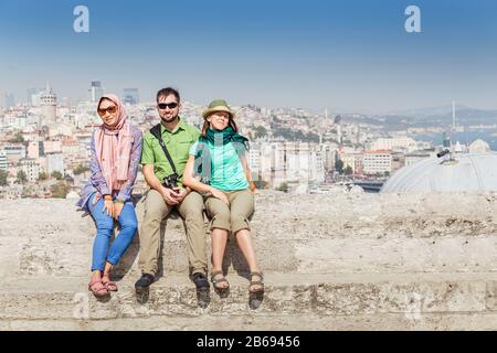 Gruppo di amici multirazziali felici seduti vicino alla moschea e godere della vista di Istanbul, Turchia Foto Stock