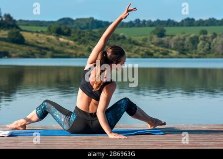 Giovane bella donna che pratica yoga, che si estende in Revolded testa a ginocchio Forward Bend esercizio, Parivrtta Janu Sirsasana posa.Sano stile di vita conc Foto Stock