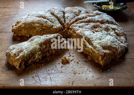 Pane di soda irlandese fatto in casa con burro e coltello. Su tavola di legno. Foto Stock