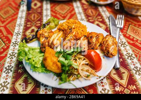 Vista piatta del piatto nel ristorante con ali di pollo fritte con bulgur e verdure. Cucina tradizionale turca Foto Stock