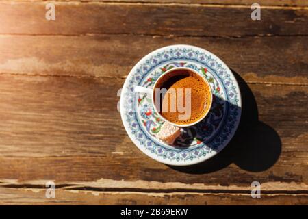 Autentico caffè turco tradizionale in una tazza con motivi nazionali su un tavolo di legno in un ristorante locale Foto Stock