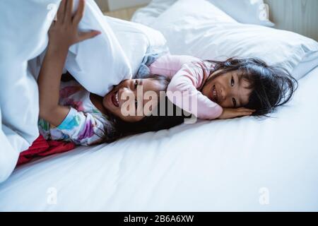 due ragazze piccole che si divertono e ridono a letto quando si svegliano Foto Stock