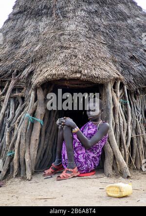 Toposa tribù donna sedersi all'ingresso della sua capanna, Namorunyang Stato, Kapoeta, Sudan del sud Foto Stock