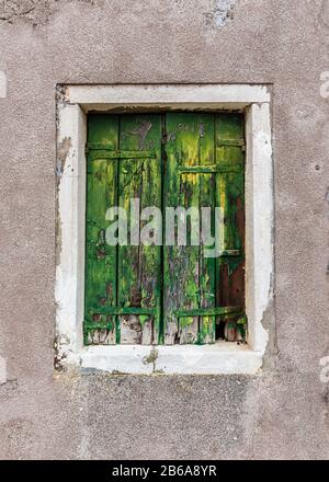 Vecchie persiane finestra verde abbandonate con vernice verde sfaldante. Sulla piccola isola di Murano, vicino a Venezia Foto Stock