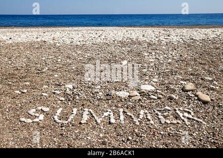 Word estate steso da ghiaia in spiaggia. Testo estate Foto Stock