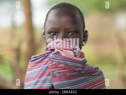 Ritratto di una ragazza Toposa che copre la bocca, Stato di Namorunyang, Kapoeta, Sudan del Sud Foto Stock