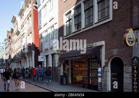 Vista sulle persone che camminano su Warmoesstraat Street ad Amsterdam. E' una delle strade piu' antiche con molti caffe', ristoranti e negozi. È una somma soleggiata Foto Stock