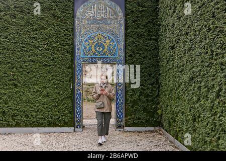 Una giovane donna turistica ha camminato attraverso un cancello in un muro verde pianta in un parco a Istanbul, Turchia. Foto Stock