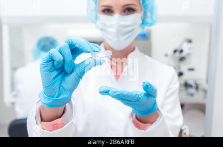 Scienziato in biolab che mostra il vaccino per una malattia Foto Stock