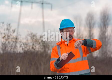 Tecnico forestale che controlla sul suo orologio intelligente mentre lavora all'aperto nella foresta Foto Stock