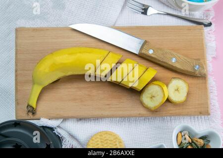 La banana affetta su un vassoio di legno, accanto alla ciotola dell'insalata sono i sandnut di mandorle e i semi di zucca Foto Stock
