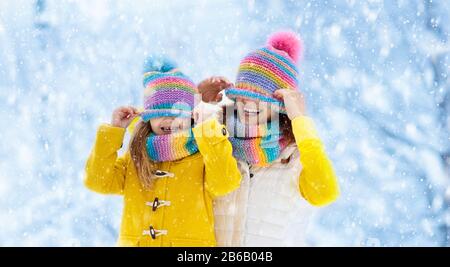 La madre e il bambino in maglia inverno cappelli giocare nella neve sulla famiglia vacanze di Natale. Fatte a mano cappello di lana e sciarpa per mamma e bambino. Maglia per bambini. Kni Foto Stock