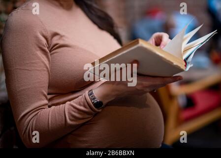 Donna incinta che legge il vecchio libro all'interno del caffè Foto Stock