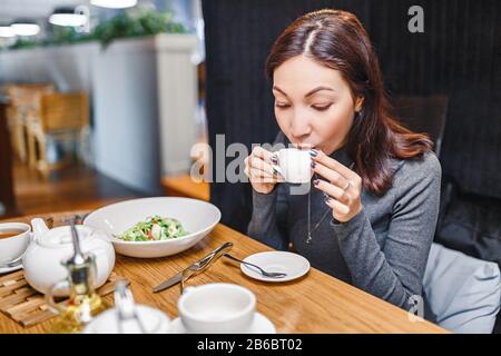 Giovane donna orientale che beve un forte aroma di caffè in un caffè Foto Stock
