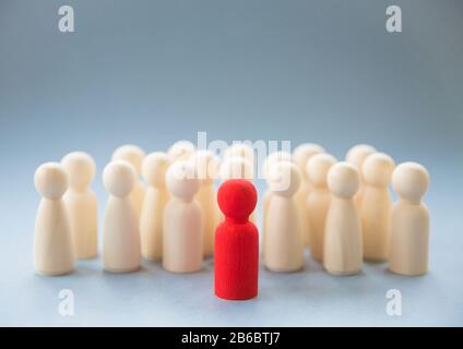 Un'immagine concettuale di una persona che si levano in piedi fuori da una folla come capo o insegnante di ispirazione fra gli uomini e le donne Foto Stock